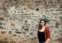 Marina Pangua: «La escritura naz nel temblor d’aquello que ye cuasi invisible» Marina Pangua delante de una pared de piedra