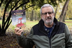 Xavier Frías Conde col llibru "El xigante llorón". Al fondu, prau y árboles.